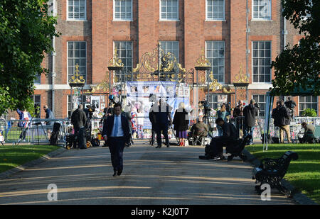 Media raccogliere fuori Kensington Palace a Londra come fiori e omaggi in occasione del ventesimo anniversario della morte di Lady Diana, principessa di Galles, sono a sinistra. Foto Stock