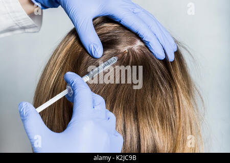 Medico aesthetician in blu guanti medicali rende acido ialuronico ringiovanimento iniezioni di bellezza nella parte posteriore della testa del biondo paziente femmina per ha Foto Stock