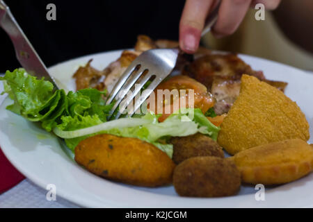 Donna che mangia Cod Salato Caccia di pesce, polpettine di gamberi e crocchette con insalata Foto Stock