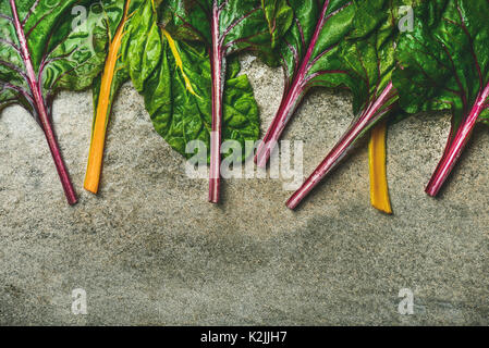 Flat-lay di fresche foglie colorate di bietole su calcestruzzo sfondo di pietra, copia spazio, vista dall'alto. Telaio di cibo. Pulire mangiare, Vegana Vegetariana, al Foto Stock