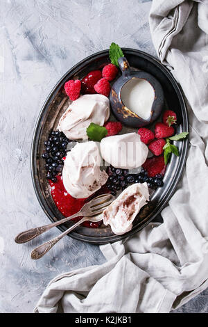 Tradizionale dessert estivo Eton Mess. Meringa, brocca di crema, marmellata di frutti di bosco freschi mirtilli, lamponi sul vassoio vintage, decorato con foglie di menta ov Foto Stock