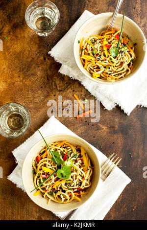 Asian Sesamo Insalata di pasta fredda servita con vino bianco. Fotografato su un marrone/sfondo nero. Foto Stock