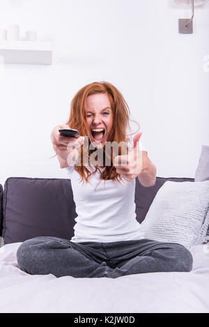 Bella e giovane redheaded donna gradisce il programma TV Foto Stock