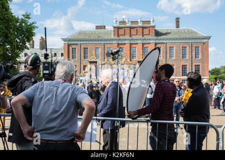 Un news reporter e cameraman con un pezzo alla telecamera fuori dalle porte di Kensington Palace. Per commemorare la Principessa Diana, venti anni dopo la sua morte. Foto Stock