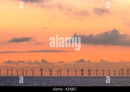 Orange dawn sky con qualche nuvola sul mare del Canale della Manica e il Thanet per centrali eoliche offshore. Fila di turbine eoliche all'orizzonte. Foto Stock