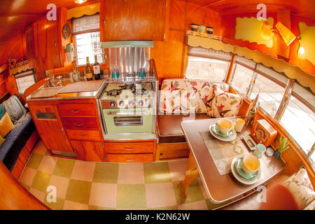 Il minuscolo pannellate di legno interno di un classico 1962 Airflyte Shasta rimorchio è dotato di tutti i comfort di casa tra cui le piastrelle di linoleum, lettino, lavello, fornello a gas e tinello. Foto Stock