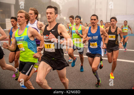 Multirazziale adulti sprint dalla linea di partenza in un inizio di mattina piede in gara su una strada in Newport Beach, CA. Foto Stock