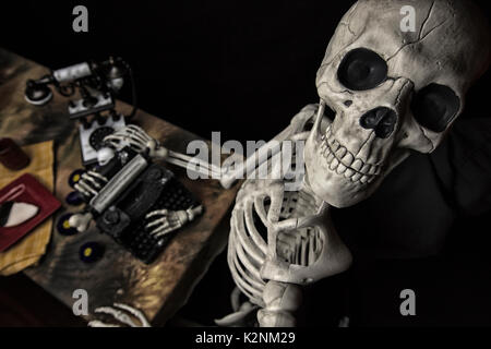 Umano scheletro di Halloween con una macchina da scrivere, telefono e cookie su una piastra Foto Stock