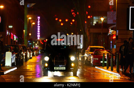 Vivace centro città street scene dopo la pioggia con strade bagnate e riflessioni e molte luci colorate e a Chinatown Foto Stock