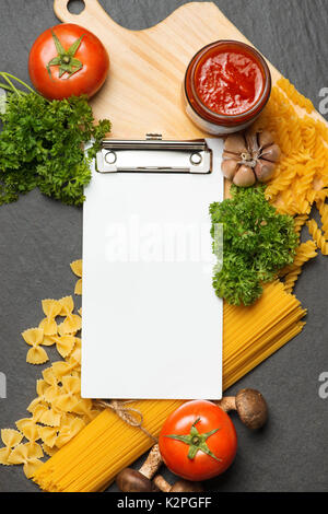 Italiano Foto di spaghetti ricetta. Fermo mockup sul tavolo di cucina circondato con prodotti. Foto Stock