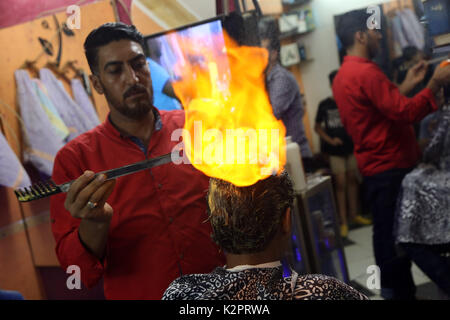 La striscia di Gaza, Egitto. 01 Sep, 2017. Un barbiere di stili i capelli dei clienti con palle di fuoco in un barbiere situato in un quartiere di dell'Egitto Giza provincia nei pressi della capitale del Cairo su il 30 agosto 2017. Vedendo le fiamme del fuoco sulla sommità di una testa della cliente non è una scena comune in barbershops in qualsiasi parte del mondo, ma è ormai sempre più familiare e interessanti in 'ultimo taglio di capelli' store in un quartiere in Egitto Giza provincia nei pressi della capitale del Cairo. Credito: Xinhua/Alamy Live News Foto Stock