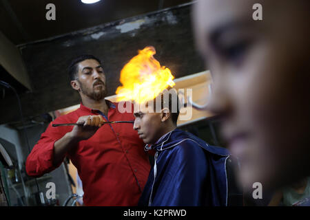 La striscia di Gaza, Egitto. 01 Sep, 2017. Un barbiere di stili i capelli dei clienti con palle di fuoco in un barbiere situato in un quartiere di dell'Egitto Giza provincia nei pressi della capitale del Cairo su il 30 agosto 2017. Vedendo le fiamme del fuoco sulla sommità di una testa della cliente non è una scena comune in barbershops in qualsiasi parte del mondo, ma è ormai sempre più familiare e interessanti in 'ultimo taglio di capelli' store in un quartiere in Egitto Giza provincia nei pressi della capitale del Cairo. Credito: Xinhua/Alamy Live News Foto Stock