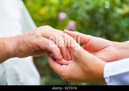 Close up giovani donne medico azienda anziani disabili dell'uomo mano tremante Foto Stock