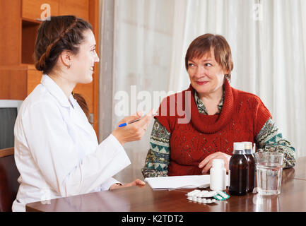 Donna sorridente medico paziente ascolto a tavola. Focus su doctor Foto Stock