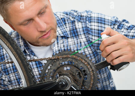Close-up di giovane uomo di lubrificazione catena per bicicletta Foto Stock