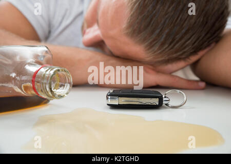 Close-up di uomo ubriaco con un bicchiere di liquore e chiave auto Foto Stock