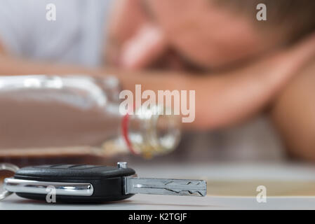 Close-up di uomo ubriaco con un bicchiere di liquore e chiave auto Foto Stock