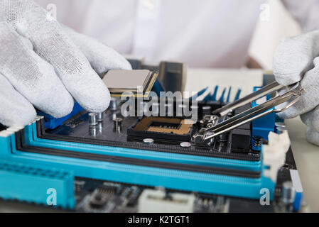 Close-up di persona le mani di installare il processore centrale nella scheda madre Foto Stock