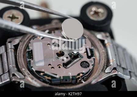 Close-up di pinzette immissione batteria su argento orologio da polso Foto Stock