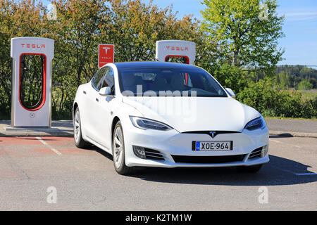 PAIMIO, Finlandia - 3 giugno 2017: Bianco Tesla Model S berlina di lusso con nuovo design all'esterno del veicolo è in carica di Tesla Supercharger Statio Foto Stock