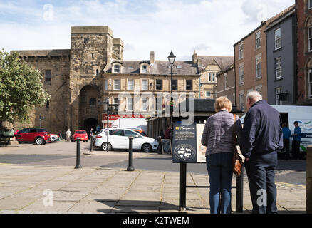 Coppia di anziani guardando il piano urbanistico entro il market place, Hexham, Northumberland, England, Regno Unito Foto Stock