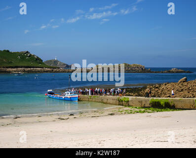 La Stella Polare preleva i visitatori giornalieri dalla città bassa quay, St Martin's, isole Scilly, con lo sfondo dell'isola di Tean e round Island li Foto Stock