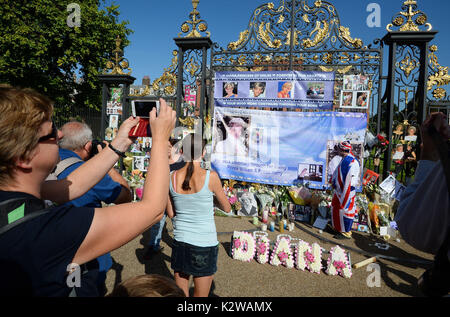 Persone fotografare fiori e omaggi in occasione del ventesimo anniversario della morte di Lady Diana, principessa di Galles, fuori Kensington Palace a Londra. Foto Stock