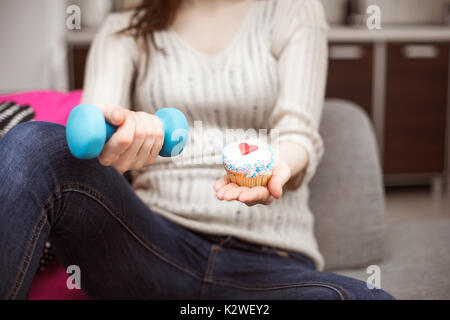 Irriconoscibile donna mostra cupcake e una hantel Foto Stock