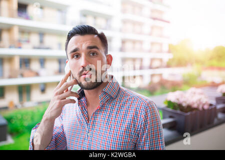 Giovane uomo elegante parlando al telefono al balcone con vista Foto Stock