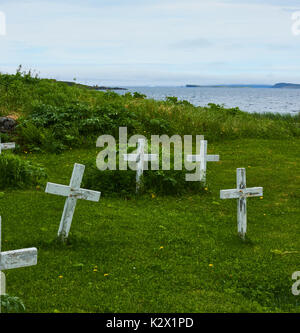 Croci di legno sulle tombe non marcate accanto all'Oceano Atlantico con gli iceberg in background, Grande Penisola Settentrionale, Terranova, Canada Foto Stock