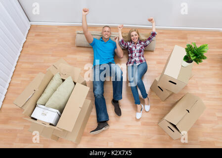 Angolo di Alta Vista di entusiasti Coppia Giovane rilassante SUL TAPPETO ARROTOLATO Foto Stock