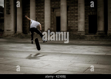 Guidatore di skateboard getting aria - via la terra a metà stunt Foto Stock