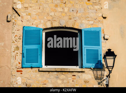 Persiane in blu chiaro con una lampada posta su una parete rustico in Provenza, Francia Foto Stock