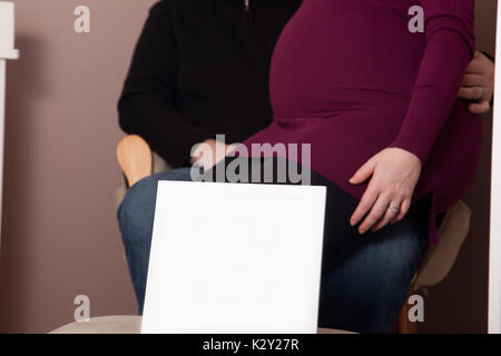 Un blank foto o segno con un paio dietro di esso, la donna è incinta a casa Foto Stock