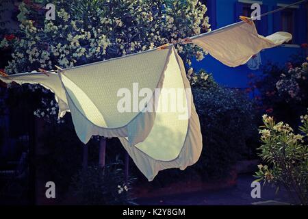 Lenzuola sparse asciugare al sole in un piccolo villaggio nell'area mediterranea Foto Stock