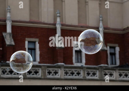 Gli edifici intorno alla piazza medievale del Rynek Glowny nella città vecchia di Cracovia in Polonia si riflettono in una bolla di sapone creata da un busker, foto Foto Stock
