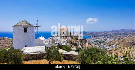 Mulino a vento tradizionale e case colorate in Syros Island, Grecia. Foto Stock
