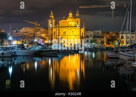 La bellissima Msida Chiesa Parrocchiale a notte profonda con il porto in primo piano. Malta. Foto Stock