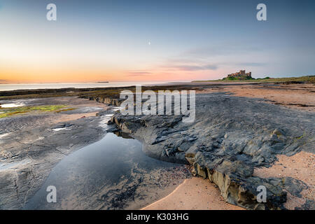 La bassa marea sulla spiaggia presso il castello di Bamburgh sulla costa di Northumberland Foto Stock