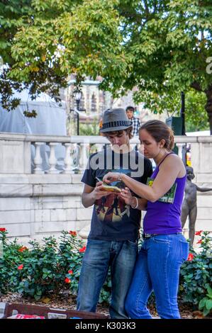 Una giovane coppia guardare un libro usato in corrispondenza di un supporto del fornitore esterno in un parco in Mount Vernon a Baltimore Book Festival, Baltimore, Maryland, 2013. Foto Stock