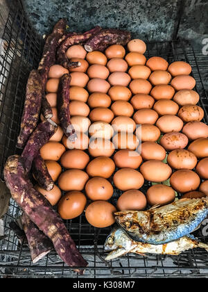 Primo piano Thailandia tradizionale cibo di strada: Grigliate/pollo arrosto uova, dolce taros, sgombro pesce e il mais alla brace stufa sul cellulare Foto Stock