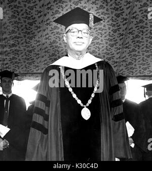 Il giorno d'inizio, Presidente della Johns Hopkins University Milton Stover Eisenhower sorge sul palco indossando tute di diploma e medaglia, cercando solenne, con i laureati in piedi dietro di lui con le mani insieme, Baltimore, Maryland, 13 giugno 1967. Foto Stock