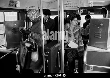 Macchina per i biglietti degli autobus 1970s di Londra all'interno dell'autobus. Pendolari e acquirenti che salgono su un autobus della London Transport. I conduttori degli autobus che distribuiscono i biglietti sono stati fermati e le biglietterie ora prendono il loro posto. 1970S UK HOMER SYKES Foto Stock