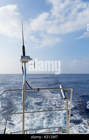 A singola asta e bobina rig in supporto guida sul ponte di offshore barche da pesca sulla giornata soleggiata con soffici nuvole. Foto Stock