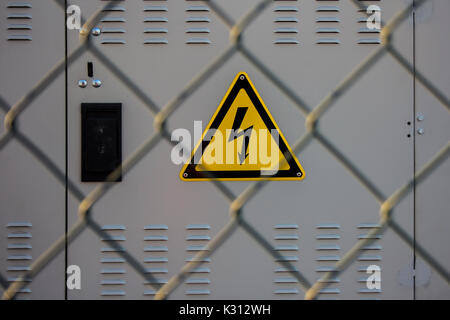 Pericolo di scossa elettrica segno posto su di una sottostazione elettrica dietro una recinzione metallica di maglia di filo Foto Stock