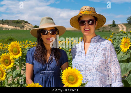 Due donne con il cappello in un campo di girasoli in estate. Las Merindades County Burgos, Castiglia e Leon, Spagna, Europa Foto Stock