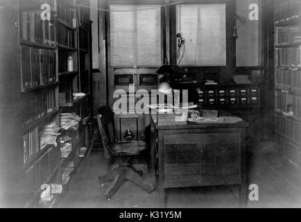 Seppia fotografia della parte interna del secondo piano ufficio del bibliotecario e segretario di reparto all'edificio di chimica del vecchio Campus della Johns Hopkins University, mostrando una scrivania con sedia in centro di scaffali per libri impilati con file e documenti, Baltimore, Maryland, 1924. Foto Stock