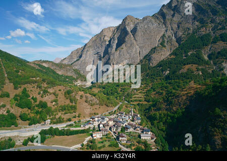 VISTA AEREA. Piccolo villaggio remoto ai piedi di una massiccia scogliera. Pontebernardo, Stura di Demonte, Provincia di Cuneo, Piemonte, Italia. Foto Stock