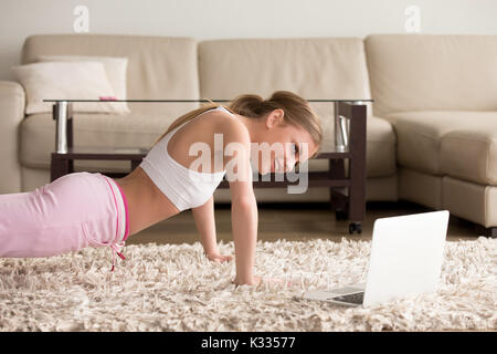 Giovane donna facendo push-up su in salotto Foto Stock