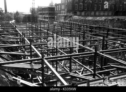 Durante le prime fasi di costruzione del Milton S Eisenhower biblioteca presso la Johns Hopkins University, travi di acciaio sono impilati e disposti in posizione dalla fondazione dell'edificio, con travi e tavole disseminate attorno al sito di sporcizia, con edifici del campus visibile in background, tra cui Krieger Hall (originariamente chiamato Rowland Hall), un laboratorio di matematica e di edificio, Baltimore, Maryland, 1963. Foto Stock